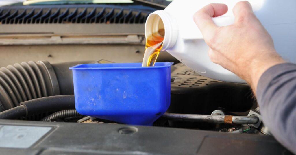 filling up engine oil with funnel